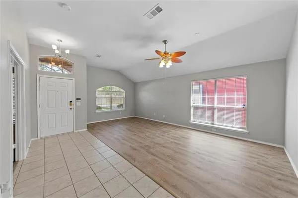 an empty room with windows and chandelier fan