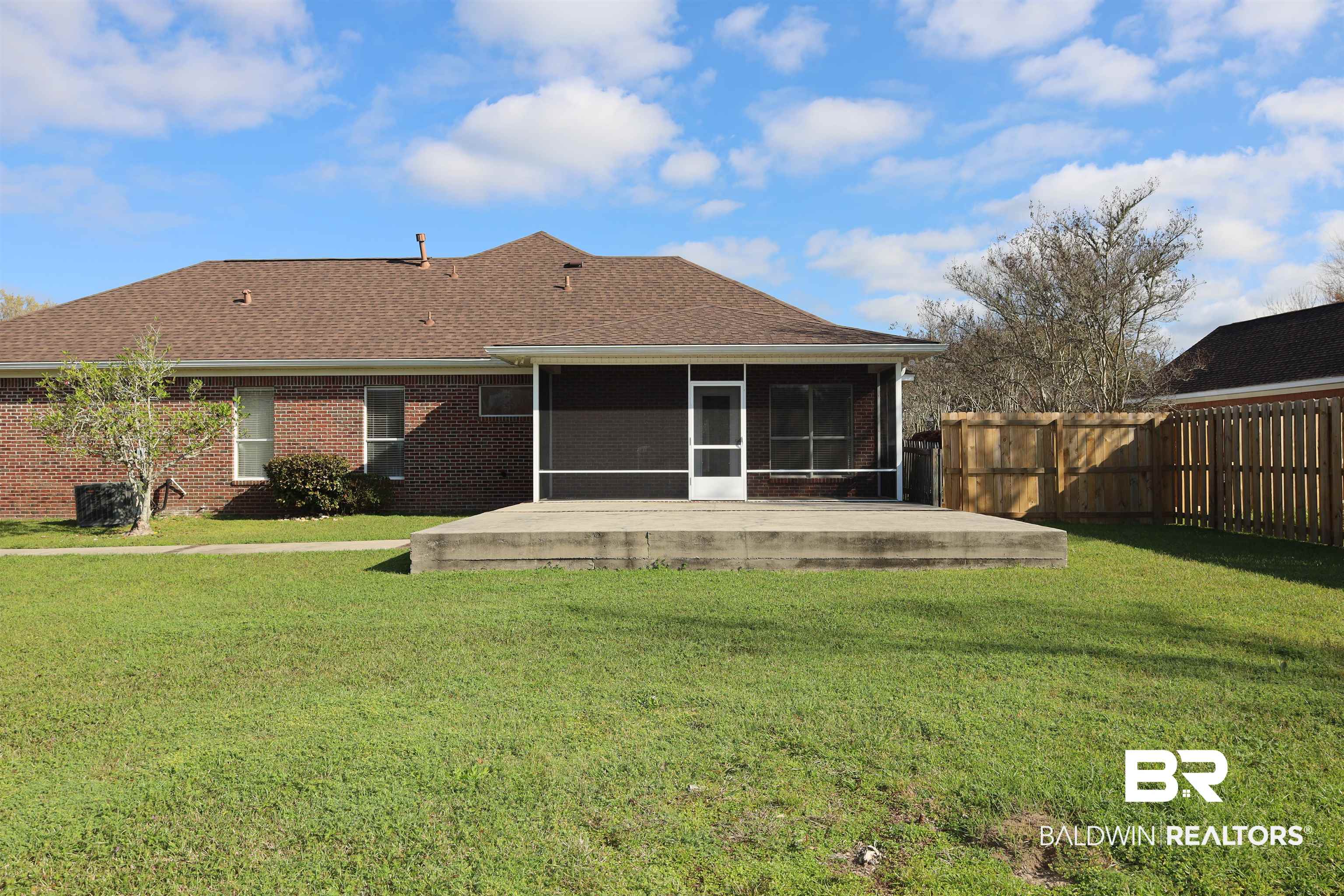 111 Destrehan Road Fairhope, AL 36532 - Photo 26 of 29 Rear view of property with brick siding, fence, a lawn, a sunroom, and a patio