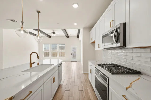 a kitchen with stainless steel appliances a sink a stove and a wooden floors