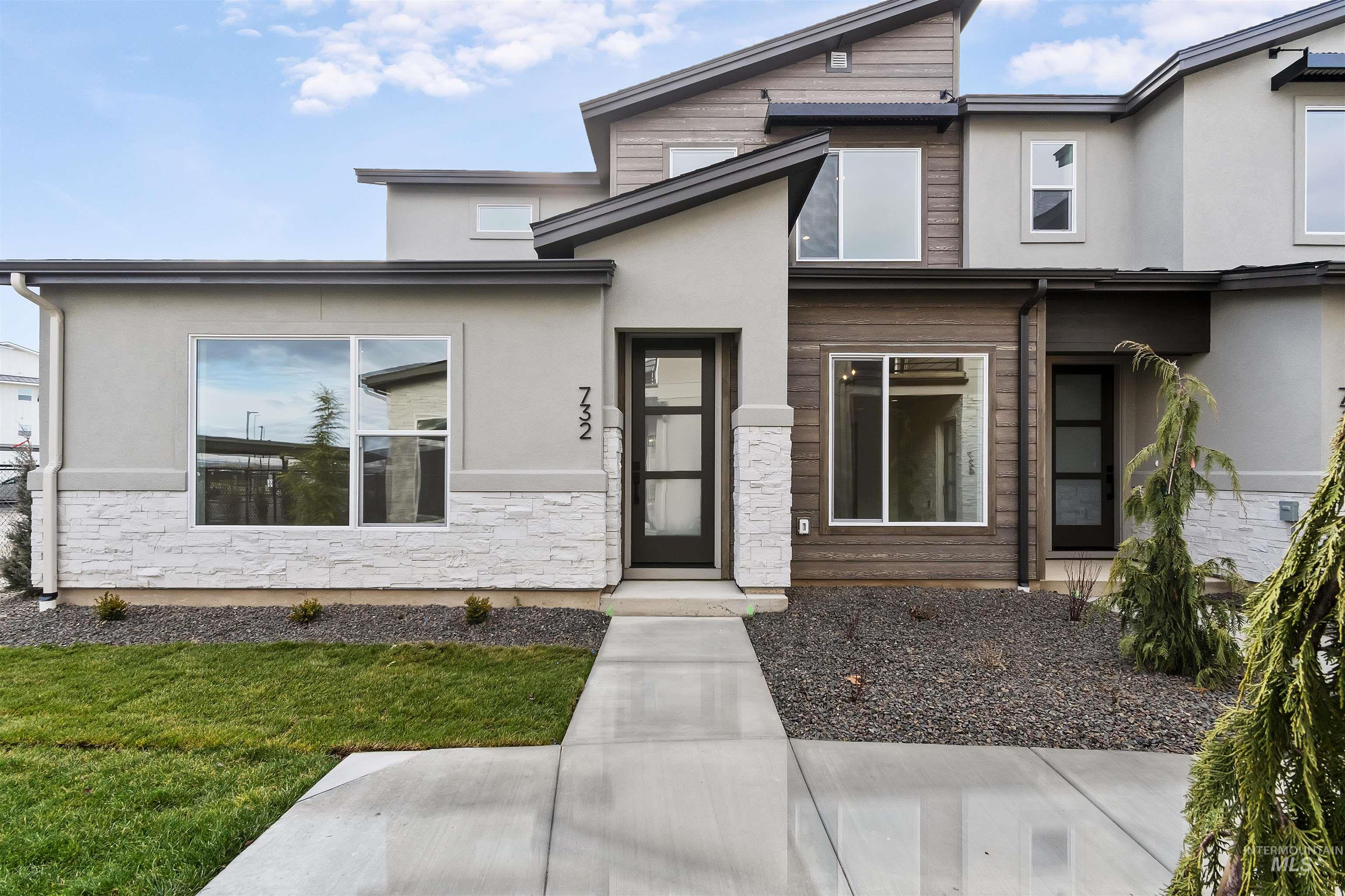 View of front of property with stucco siding, stone siding, and a front yard
