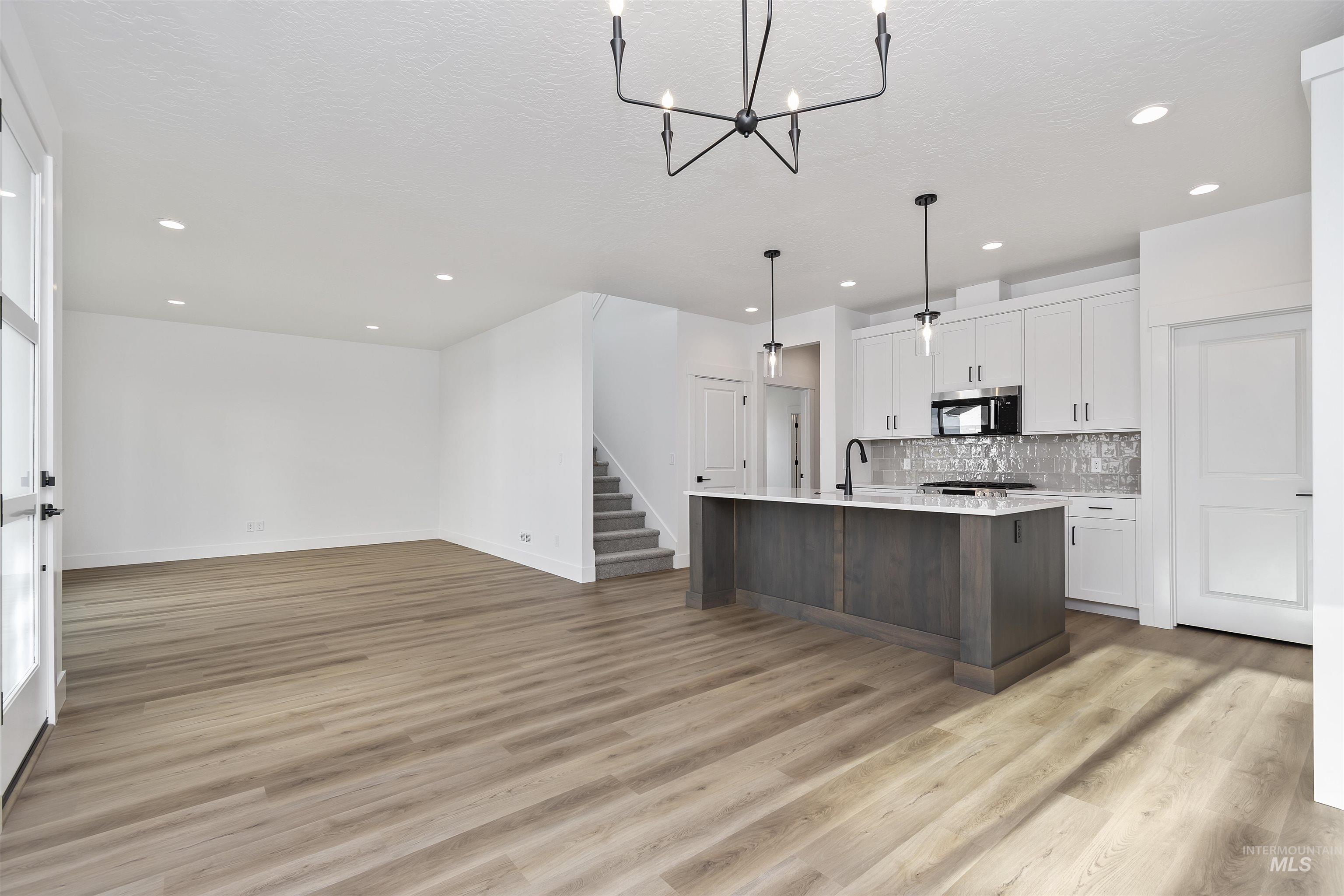 732 South Calhoun Lane Star, ID 83669 - Photo 47 of 48 Kitchen with white cabinets, open floor plan, an island with sink, light wood-style flooring, and hanging light fixtures