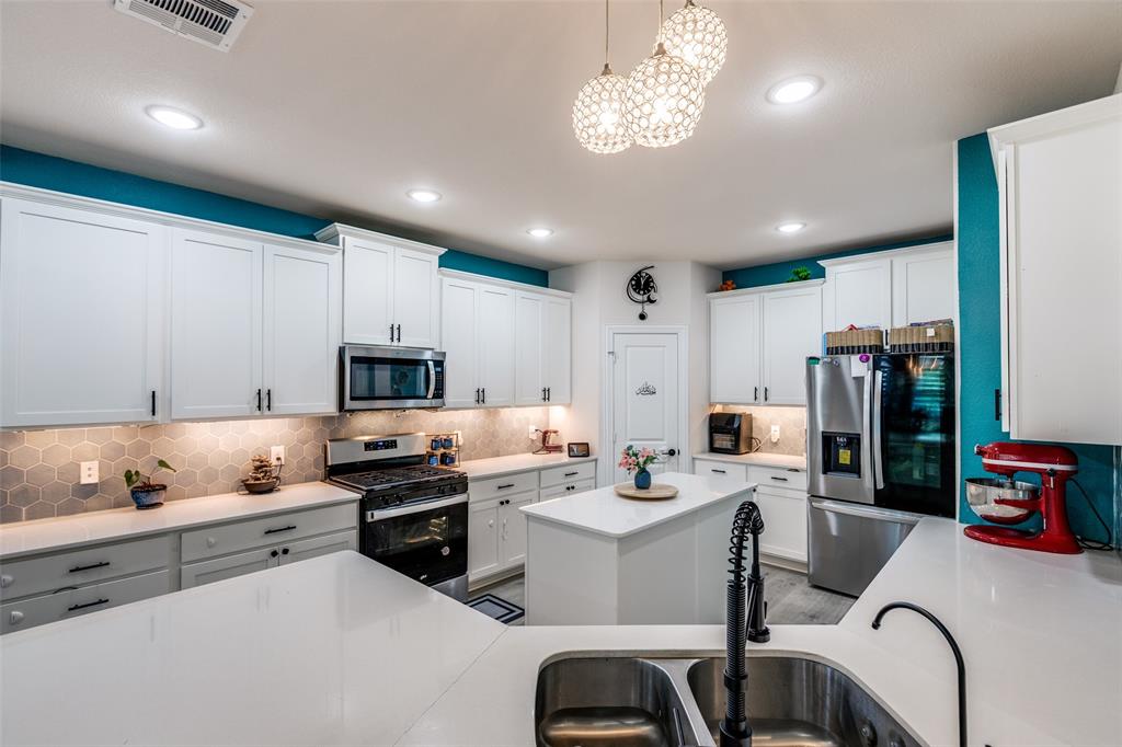 7636 Cherry Blossom Lane Little Elm, TX 76227 - Photo 6 of 31 a kitchen with a sink stainless steel appliances cabinets and a counter top space