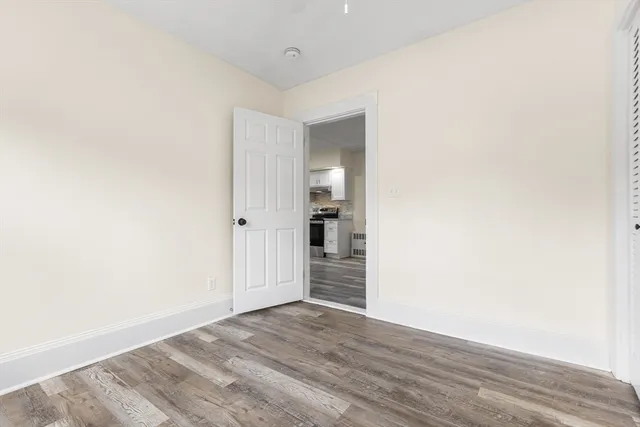 a view of an empty room with wooden floor and closet