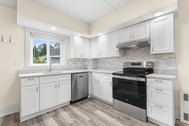 a kitchen with granite countertop white cabinets stainless steel appliances and a window