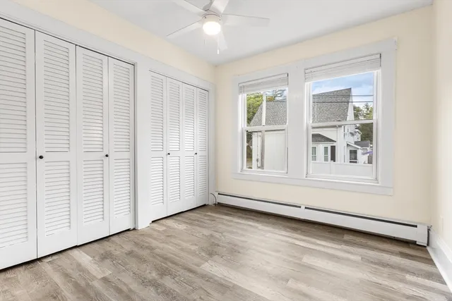 an empty room with wooden floor cabinet and windows