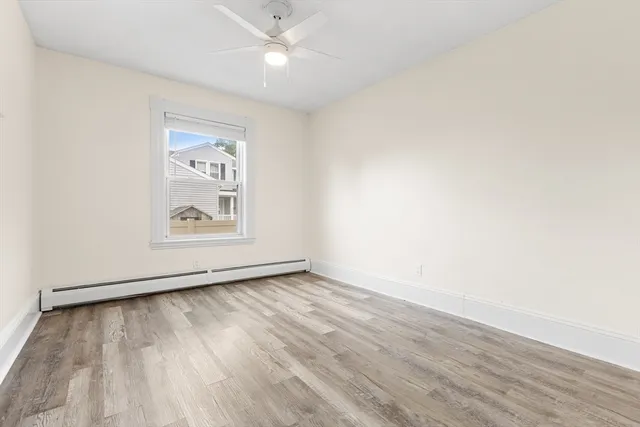 an empty room with wooden floor ceiling fan and windows