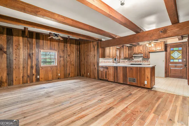 a large room with kitchen island wooden floors and stainless steel appliances