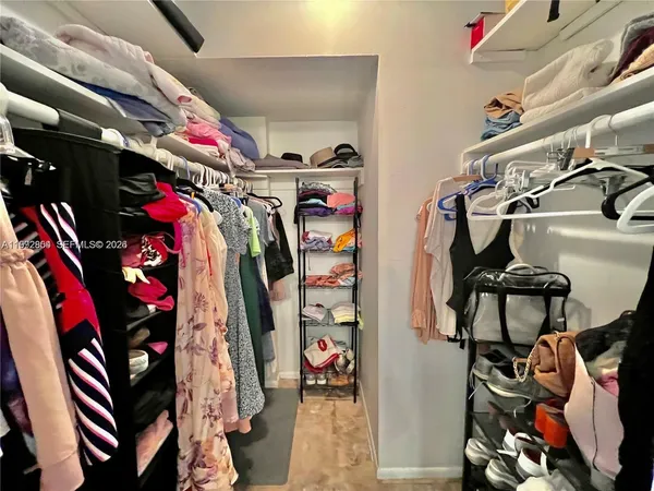 a view of walk in closet with clothes and shoes