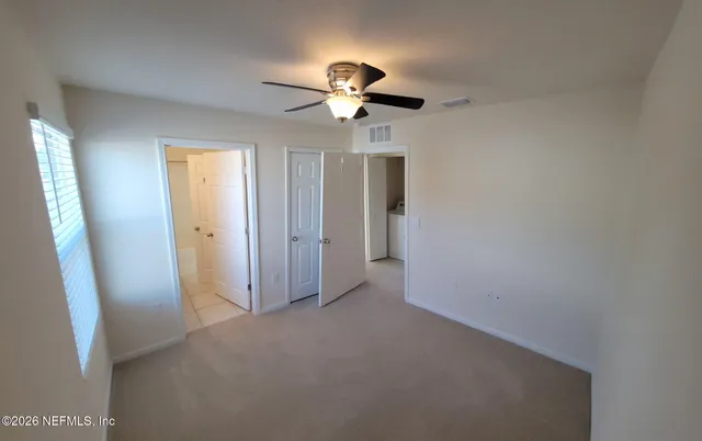 an empty room with closet and a chandelier fan