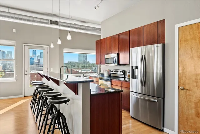 a kitchen with stainless steel appliances a refrigerator a stove a sink cabinets and a dining table