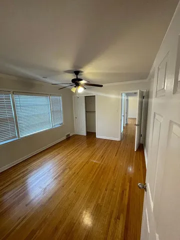 a view of empty room with wooden floor and fan