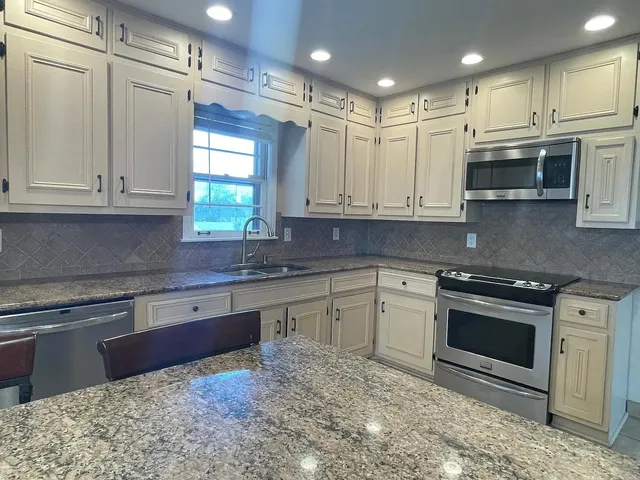 a kitchen with stainless steel appliances granite countertop a stove a sink and a microwave