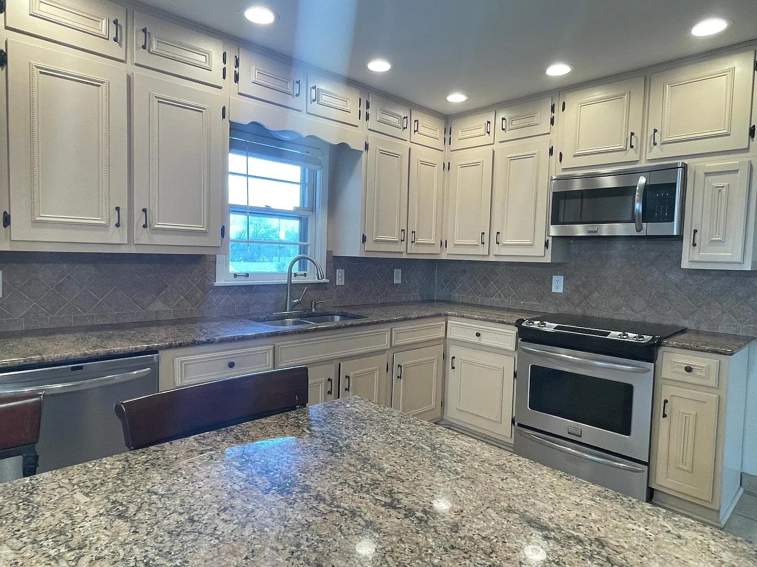 5568 Rich Road Memphis, TN 38120 - Photo 6 of 19 a kitchen with stainless steel appliances granite countertop a stove a sink and a microwave