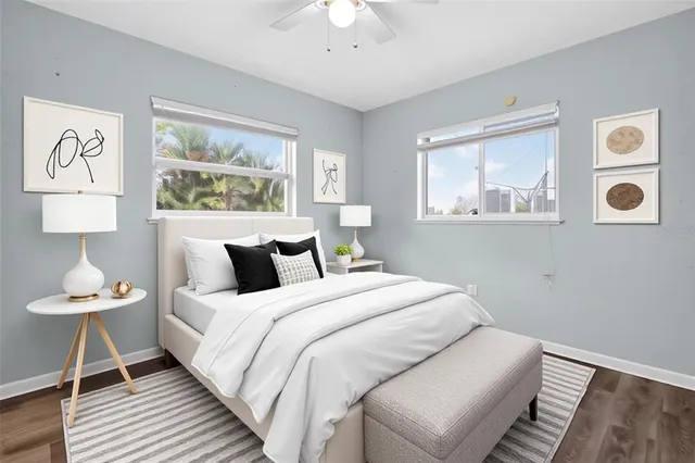a bedroom with bed and a lamp on dresser with wooden floor