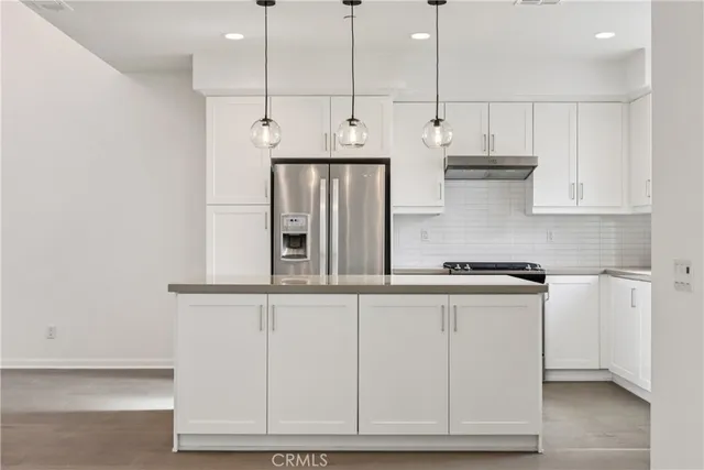 a kitchen with stainless steel appliances granite countertop a sink a stove and white cabinets
