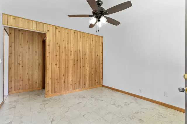 an empty room with a ceiling fan and a window