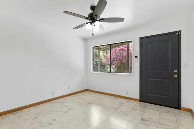 an empty room with windows and fan