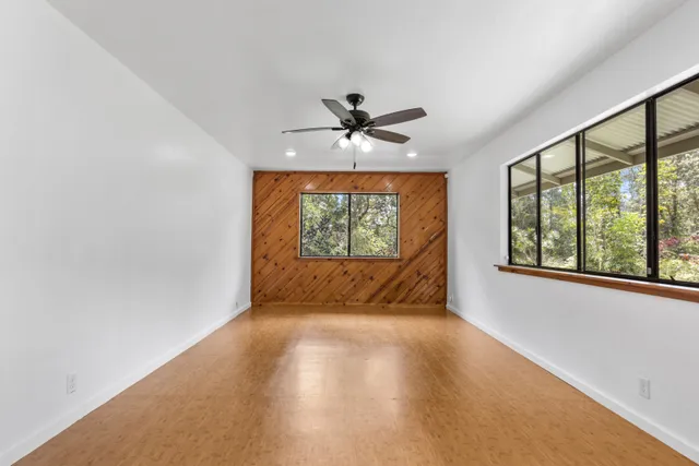 an empty room with windows and chandelier fan