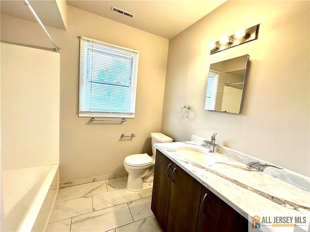 909 Hermann Road North Brunswick, NJ 08902 - Photo 7 of 11 a bathroom with a granite countertop sink toilet and mirror