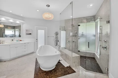 a large white bathroom with a granite countertop sink mirror and shower