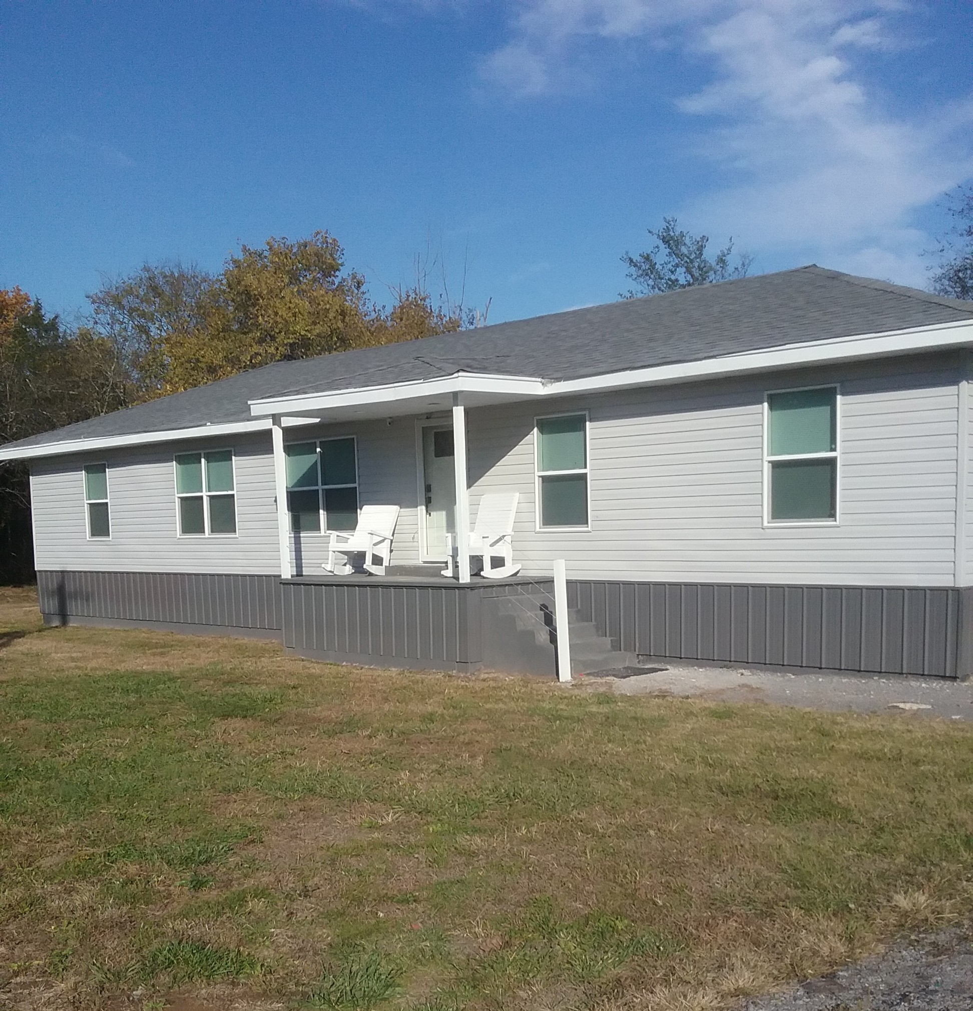 a front view of house with yard and trees in the background