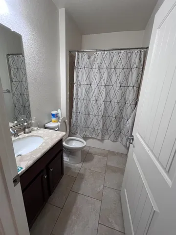 a bathroom with a granite countertop sink a toilet and a bathtub