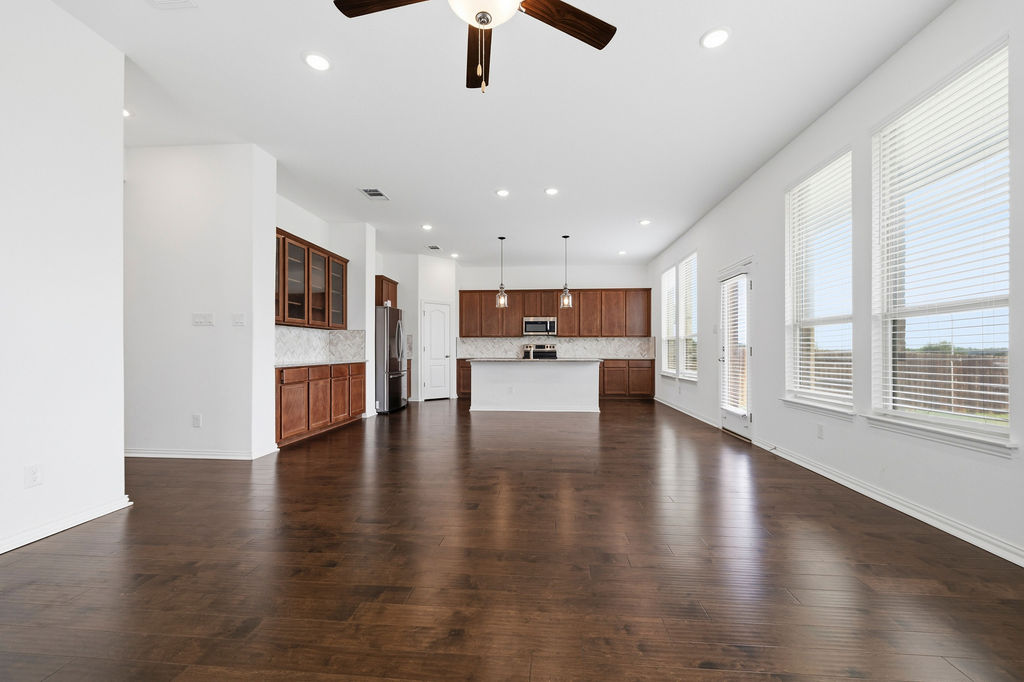 1005 Ridge Runner Drive Georgetown, TX 78628 - Photo 7 of 32 Expansive open-concept living area featuring dark wood-finish flooring, a contemporary ceiling fan, and recessed lighting