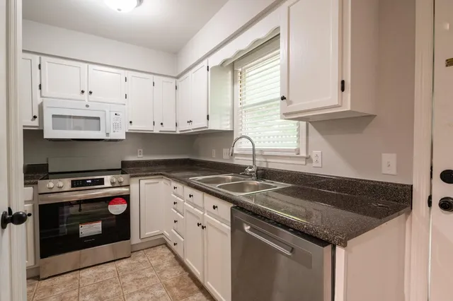 a kitchen with granite countertop white cabinets and a stove