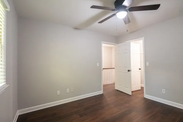 an empty room with wooden floor ceiling fan and windows