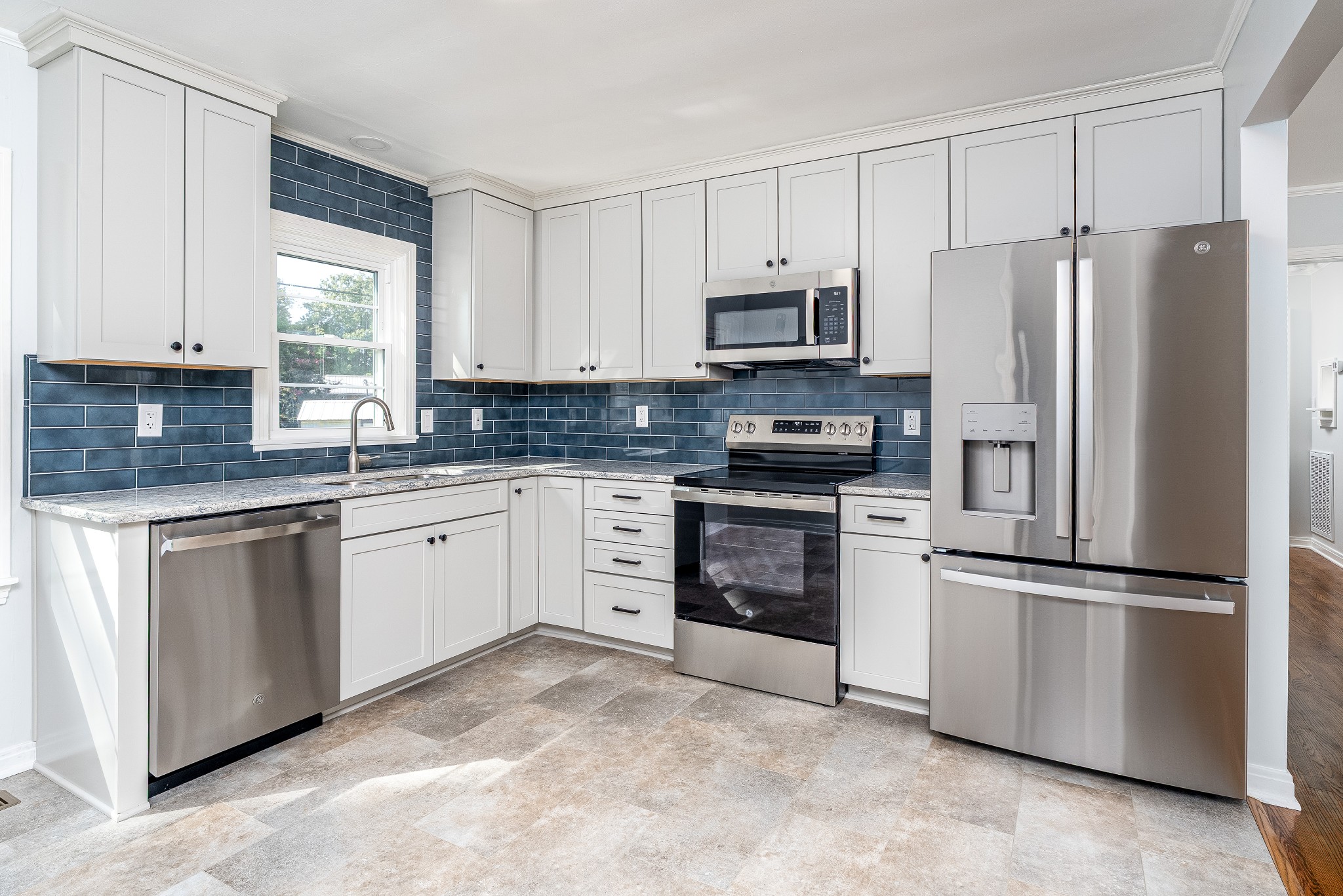 a kitchen with white cabinets stainless steel appliances and a window