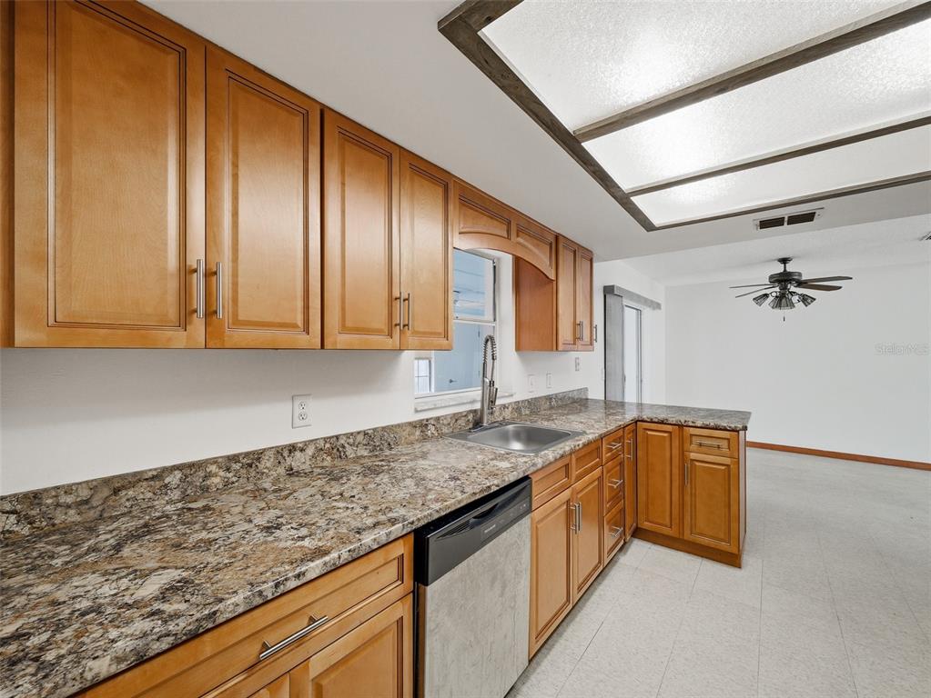 3303 Orange Tree Drive Edgewater, FL 32141 - Photo 12 of 33 a kitchen with granite countertop cabinets stainless steel appliances a sink and wooden floor