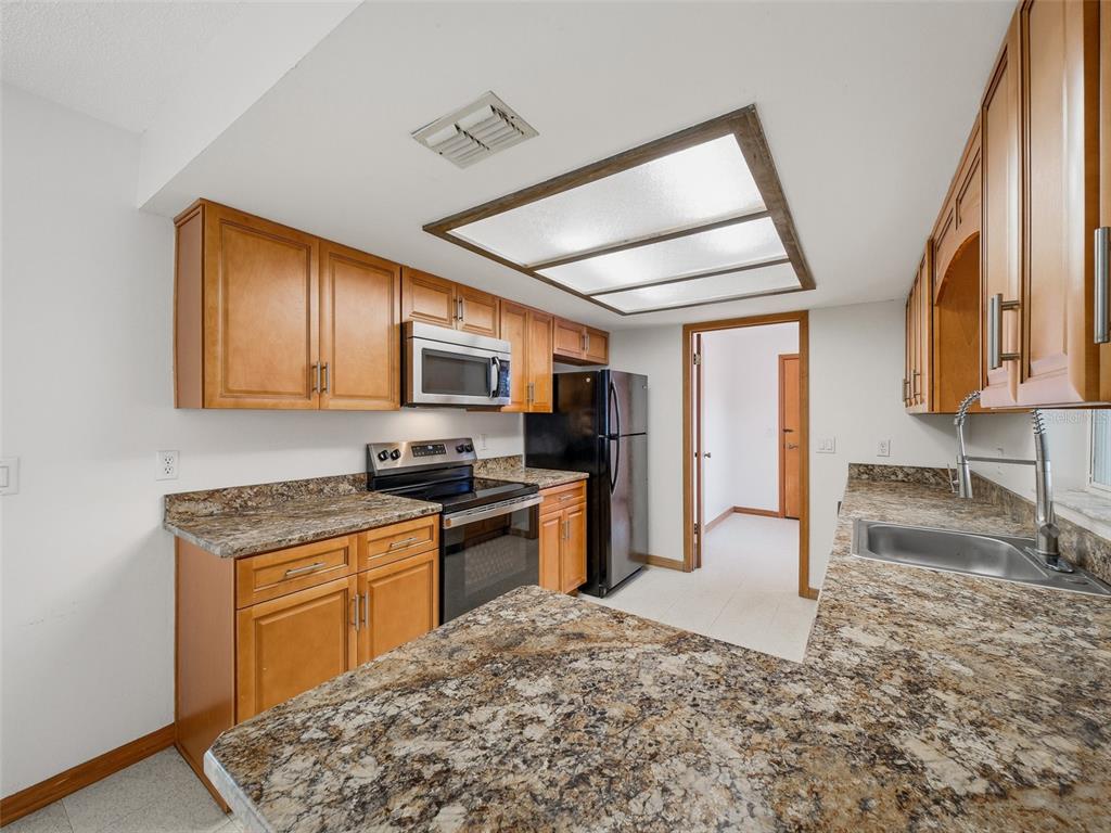 3303 Orange Tree Drive Edgewater, FL 32141 - Photo 13 of 33 a kitchen with stainless steel appliances granite countertop a stove a sink and a refrigerator
