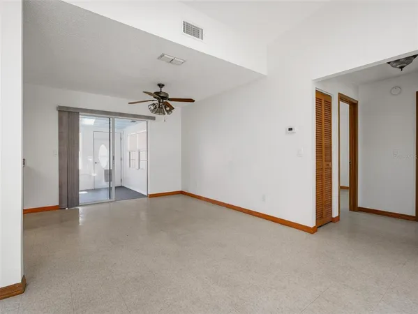 an empty room with windows and fan