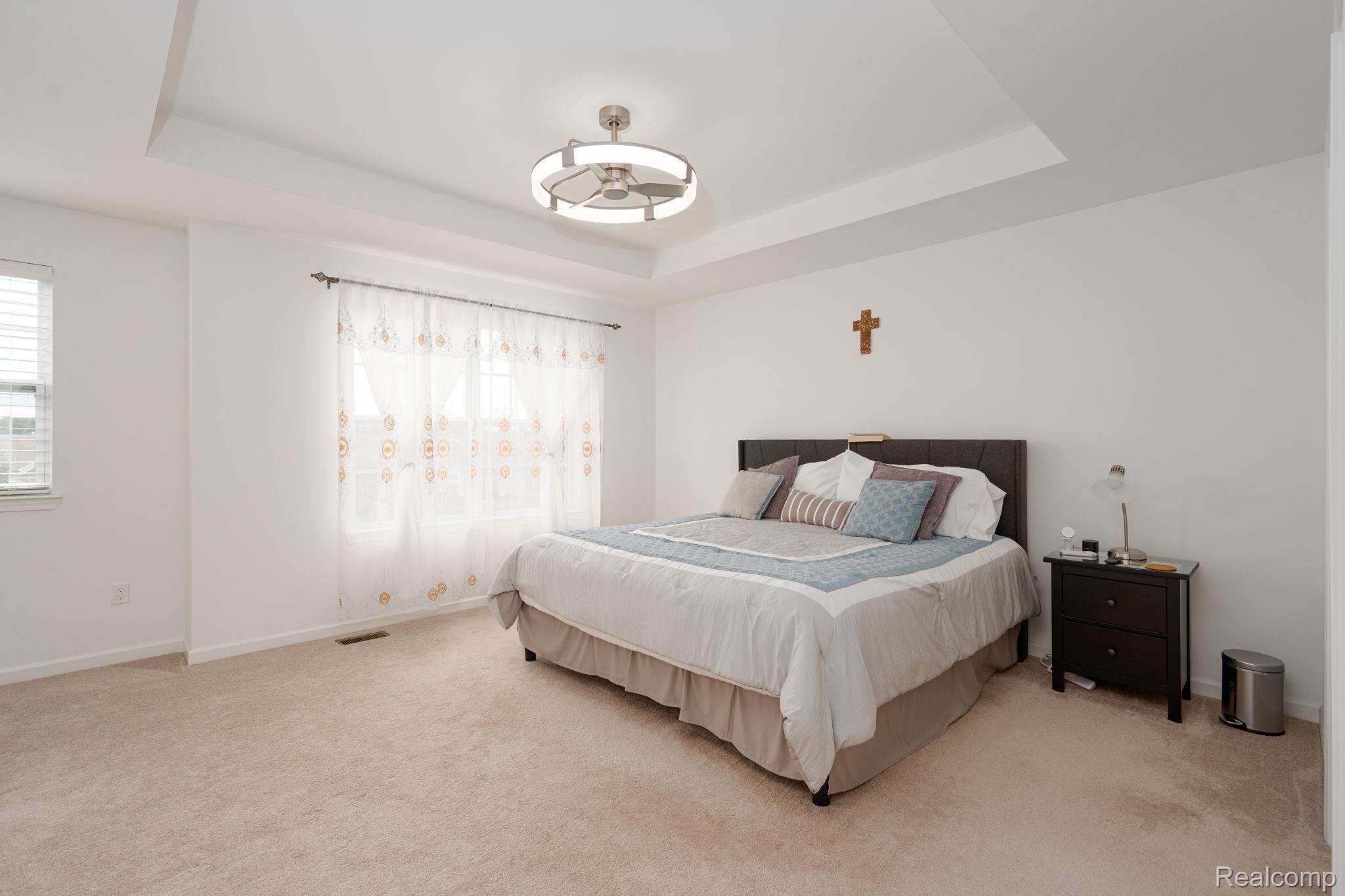 48904 Carnegie Way Macomb, MI 48042 - Photo 20 of 34 Spacious room featuring tray ceilings, neutral wall tones, plush carpeting, window blinds, and a contemporary ceiling fan with integrated lighting