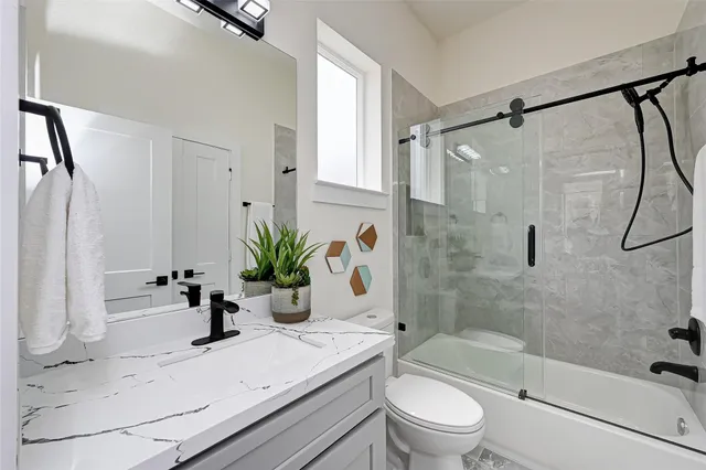 a bathroom with a granite countertop sink a toilet and shower