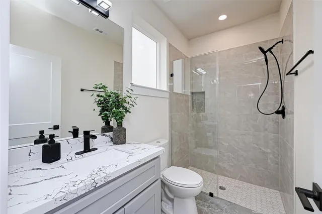 a bathroom with a granite countertop sink a toilet and shower