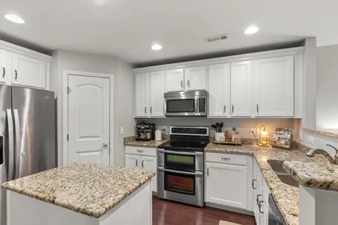 a kitchen with granite countertop a sink stove and refrigerator