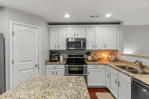 a kitchen with granite countertop white cabinets and stainless steel appliances