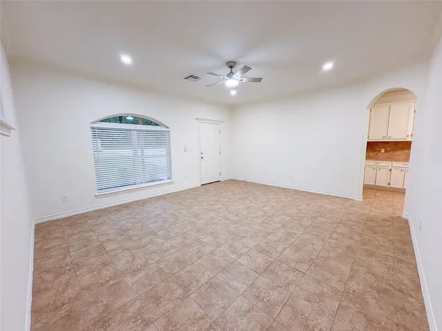 an empty room with a ceiling fan and wooden floor