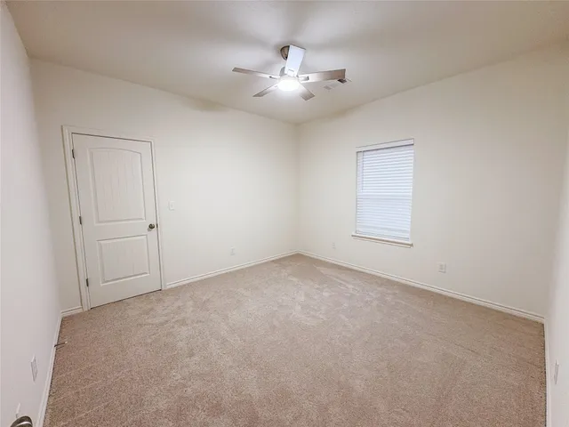 an empty room with chandelier fan and windows