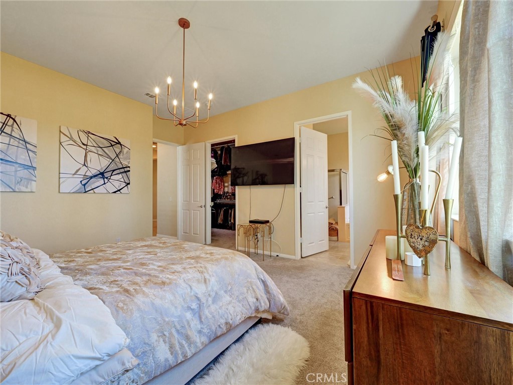 887 Westchester Road Beaumont, CA 92223 - Photo 28 of 41 a spacious bedroom with a bed and a chandelier