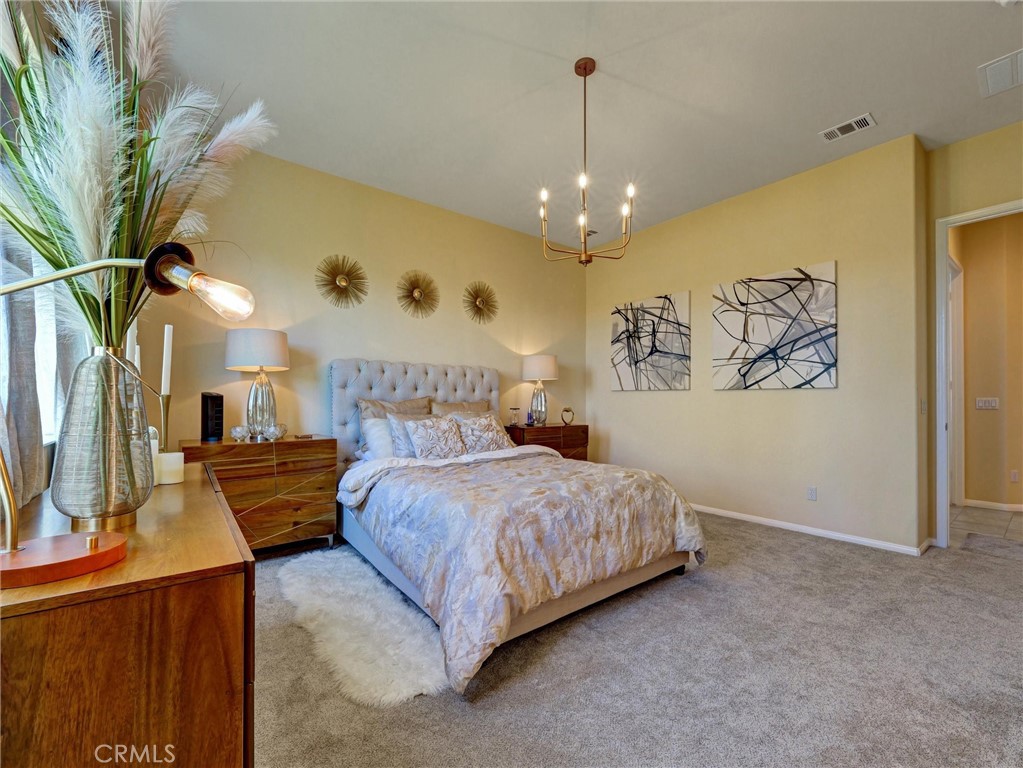 887 Westchester Road Beaumont, CA 92223 - Photo 29 of 41 a spacious bedroom with a bed and a chandelier