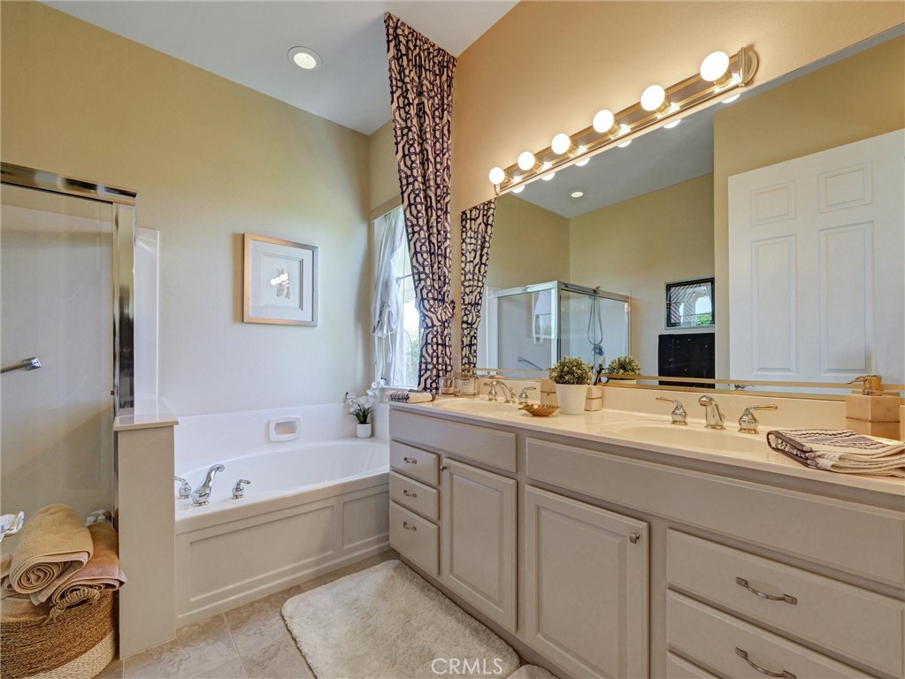 887 Westchester Road Beaumont, CA 92223 - Photo 30 of 41 a bathroom with a bathtub a double vanity sink and mirror