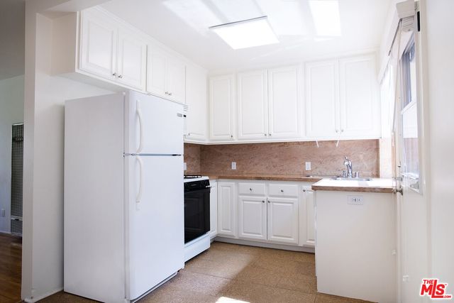 a kitchen with stainless steel appliances granite countertop a refrigerator sink and white cabinets
