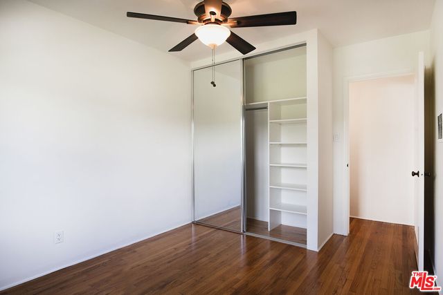 an empty room with wooden floor closet fan and windows