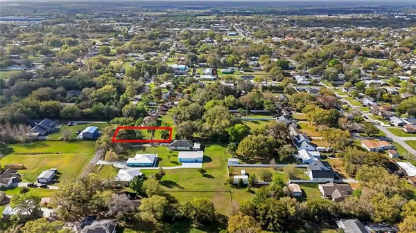 an aerial view of residential houses with outdoor space and trees
