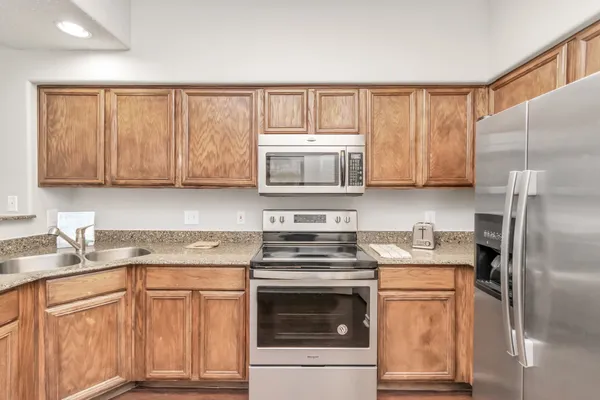 a kitchen with stainless steel appliances granite countertop a refrigerator stove top oven and sink with cabinets
