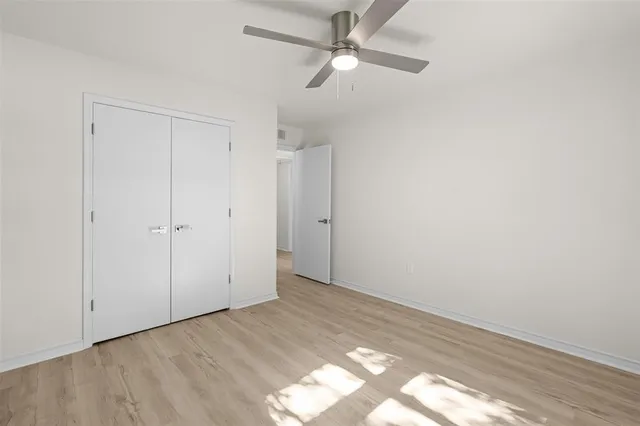 an empty room with closet and a ceiling fan