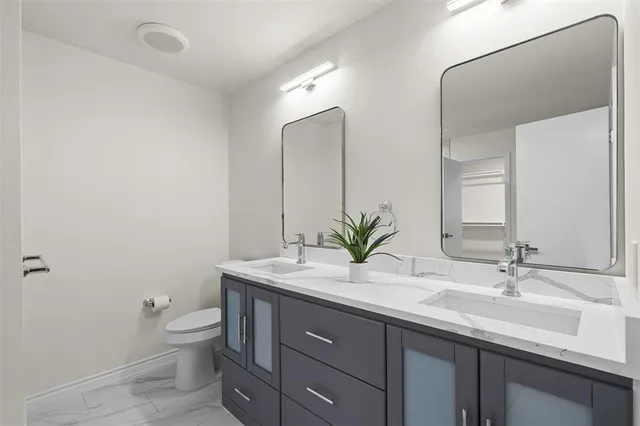 a bathroom with a granite countertop sink a toilet and a mirror