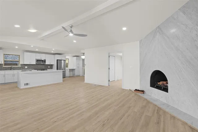 a large white kitchen with a sink a refrigerator and window